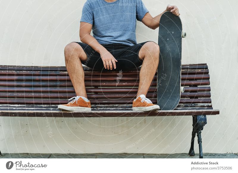 Crop Skater sitzen auf Bank in der Stadt urban Skateboard Mann sich[Akk] entspannen Stil Straße cool Generation männlich jung schäbig hölzern Großstadt ruhen