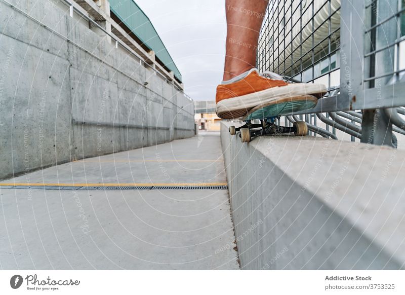 Crop Skater macht Trick auf Stein in der Stadt Skateboard Mann Großstadt Hobby Stunt Schlittschuh urban Stil Fähigkeit Talent Turnschuh cool modern Sommer