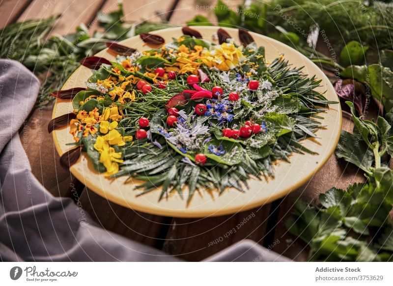 Leckeres Grünzeug mit Blütenblättern auf Teller Blume Zusammensetzung Kraut Ordnung Blütenblatt grün hölzern Tisch reif frisch Natur Sommer Blütezeit Flora