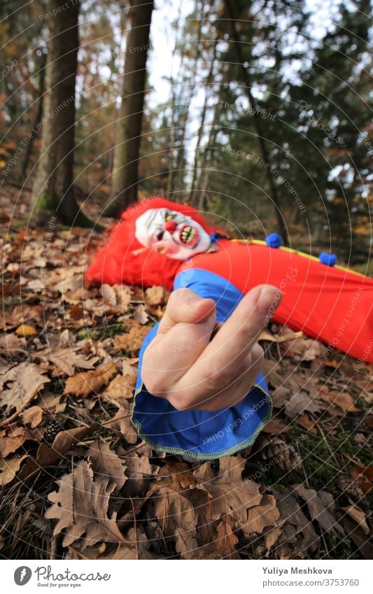 Halloween Party. Fick dich.Der böse Clown zeigt den Mittelfinger. Mittelfingergeste. gruselig Kostüm Clown Overalls rot Haare Herbst Wald Feiertage Oktober