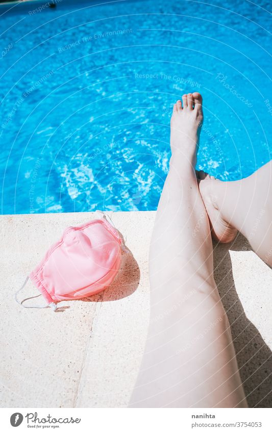 Frauenbeine in einem Schwimmbad in der Nähe einer rosa Schutzmaske Sommer COVID Pool Mundschutz Fuß Feiertage Wasser frisch Coronavirus Frische Gesichtsmaske