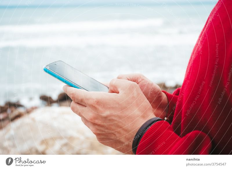 Hände halten ein neues Smartphone Hand klug Telefon Mobile Text Texten Strand Mann männlich jung Jugend Teenager Kapuze im Freien Himmel Technik & Technologie