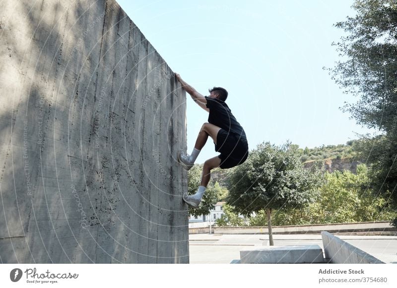 Starker Mann springt auf Gebäudemauer Le Parkour springen Stunt Freestyle Wand Trick urban Großstadt extrem Gefahr männlich Straße Mut jung aktiv gutaussehend