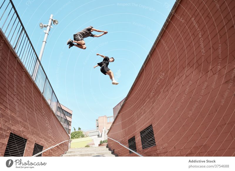 Männer springen über eine Treppe in der Stadt Le Parkour Stunt Trick Großstadt Zusammensein Treppenhaus urban extrem Gefahr Hobby Mut aktiv Aktivität