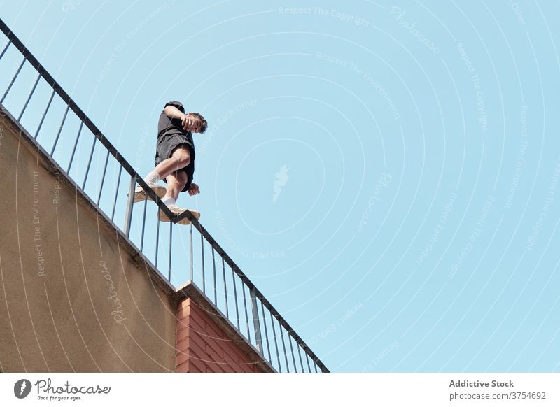 Mutiger Mann auf Metallgeländer in der Stadt Le Parkour Trick vorbereiten Gebäude Reling Großstadt urban extrem männlich jung aktiv stehen gutaussehend