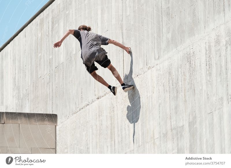 Starker Mann springt auf Gebäudemauer Le Parkour springen Stunt Freestyle Wand Trick urban Großstadt extrem Gefahr männlich Straße Mut jung aktiv gutaussehend