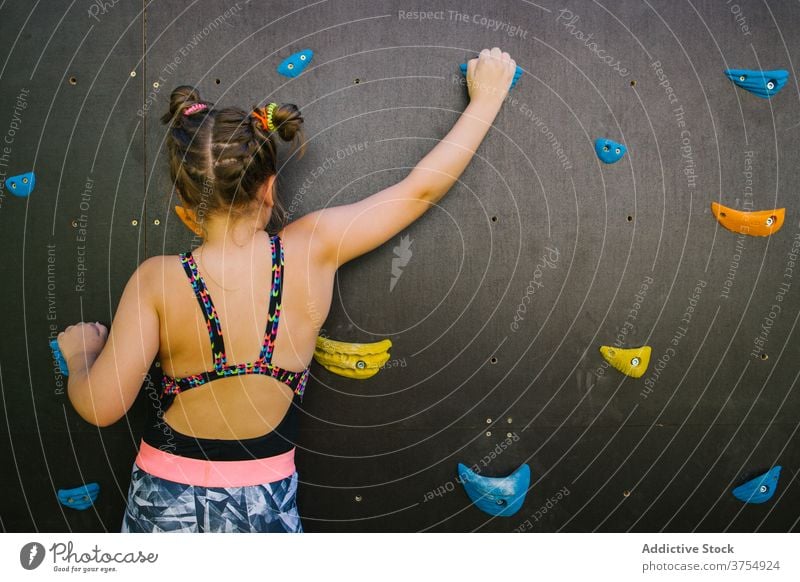 Mutiges Mädchen klettert Wand in der Turnhalle Aufstieg Kind Felsbrocken Fitnessstudio künstlich Felsen Griff Training Gleichgewicht Halt furchtlos üben Übung