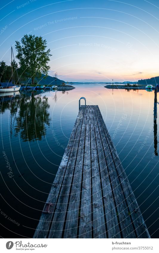 kleiner Holzsteg im Abendlicht Abendstimmung Natur Außenaufnahme Landschaft Himmel Sonnenuntergang Abenddämmerung Menschenleer Wasser Steg See Boote Segelboote