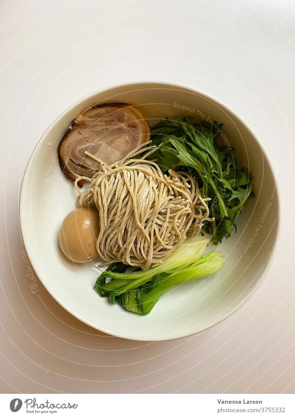 Schweinefleisch-Ramen-Zutaten in weißer Schüssel ohne Brühe. Ramennudeln Suppe Lebensmittel diy selbstgemacht Japanisches Essen Ei Nudeln Bok Choi