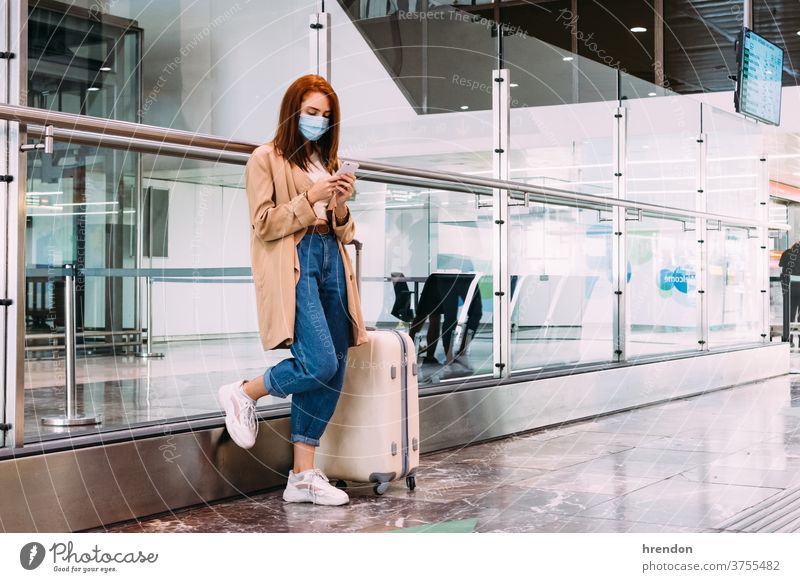 Frau mit einer Maske, die am Bahnhof mit ihrem Smartphone eine Textnachricht sendet Geschäftsfrau Anruf Arbeit Warten Transport Verkehr Öffentlich Reise Tourist