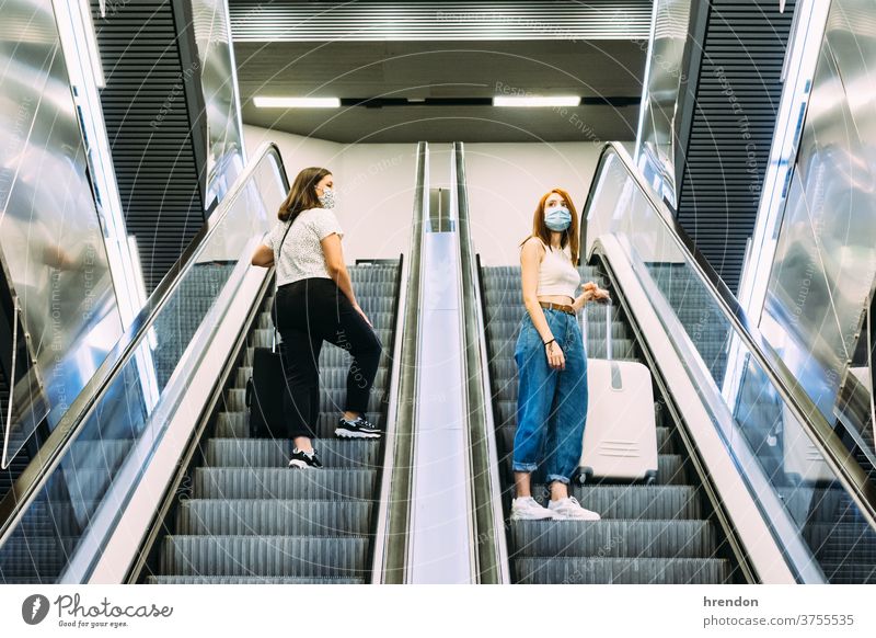 zwei junge Touristen mit Gesichtsmasken die U-Bahn-Rolltreppen benutzen Treppenhaus Terminal Coronavirus Tourismus Transport Verkehr Öffentlich Reise Ausflug