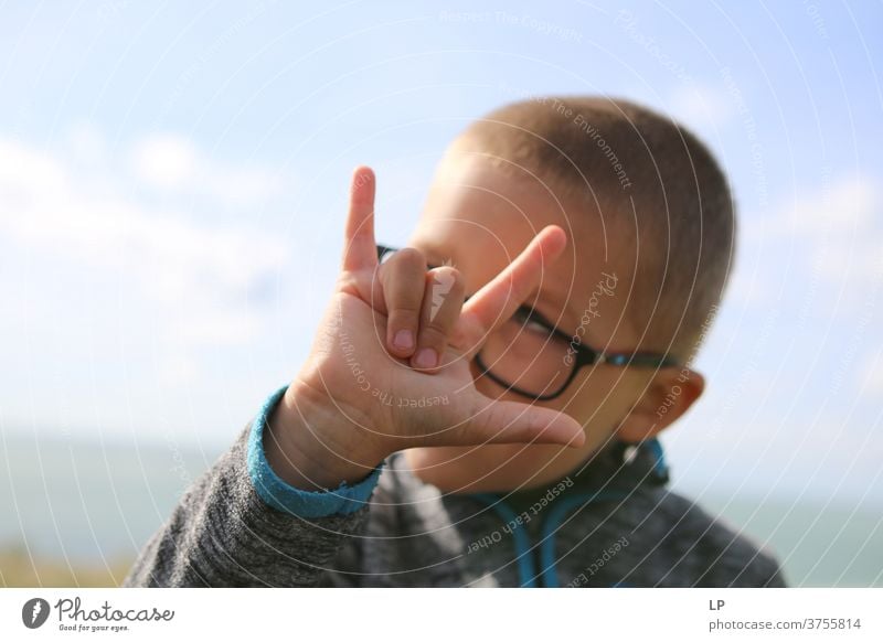 Junge macht Hornzeichen Rockmusik Hand Handbewegung Zeichen Kultur Finger Daumen kleiner Finger Zeigefinger Hinduismus Pech böser Blick Aberglaube