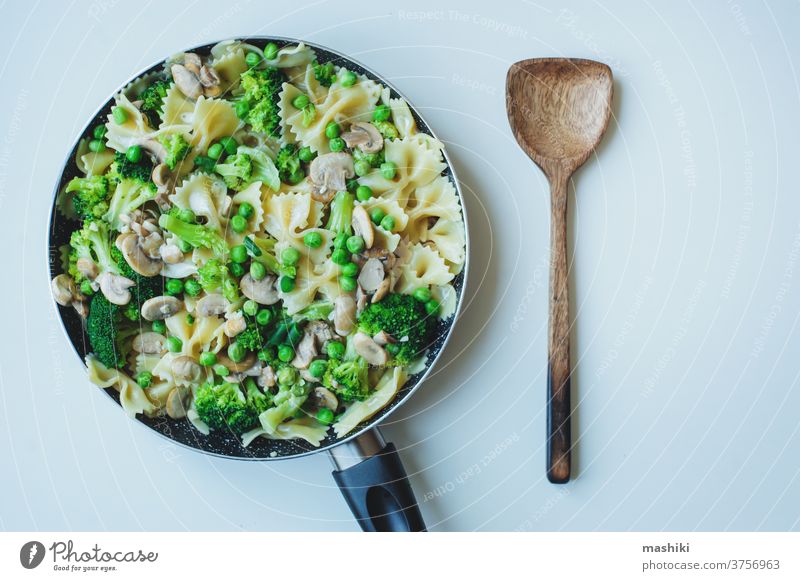 Pfanne mit gekochter schmackhafter italienischer vegetarischer Pasta mit Brokkoli, grünen Bohnen, Champignons in Sahnesoße. Schmackhaftes Mittag- oder Abendessen