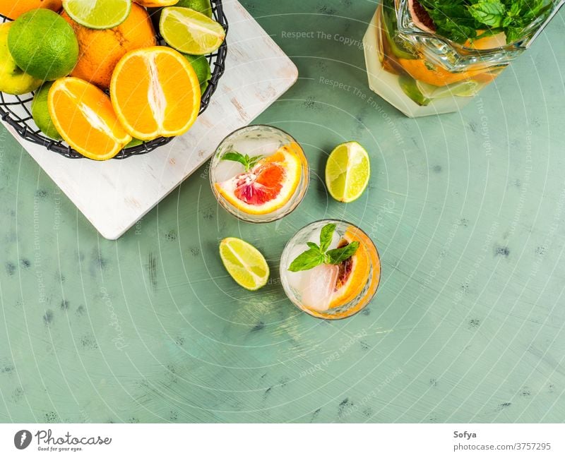 Frisches Sommer-Zitrusgetränk mit Eis auf Grün trinken Zitrusfrüchte Wasser Cocktail Limonade Entzug Mocktail Blutorange Frucht flache Verlegung Draufsicht Kalk