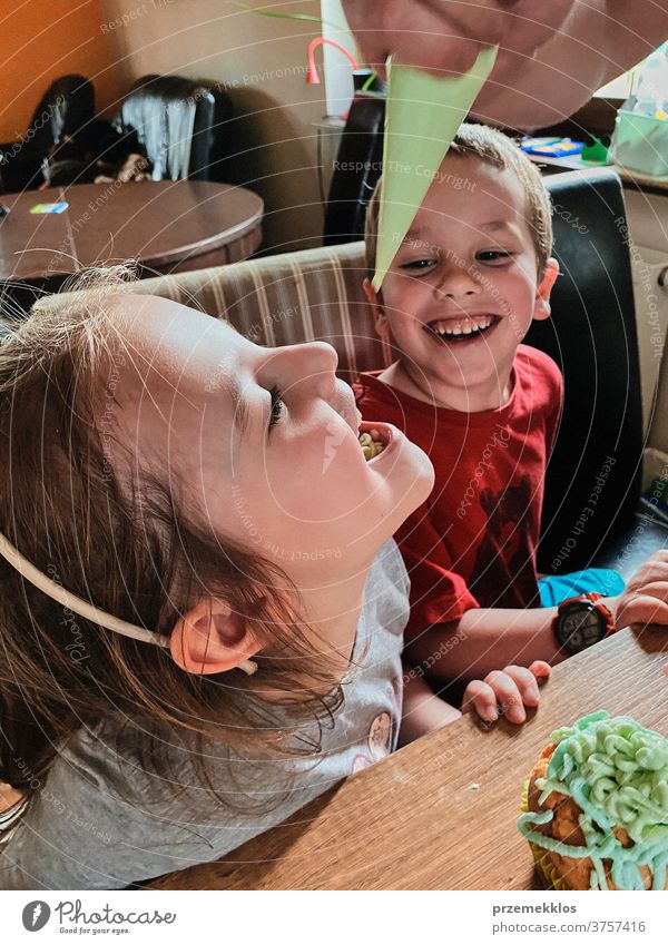 Kind isst Schlagsahne, die direkt aus der Tüte gepresst wurde Kinder backen Cupcake dekorierend Keks vorbereitend Essen zubereiten Familie heimisch Muffin