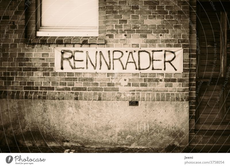 Gemauerte Wand in einer Stadt mit dem Banner "RENNRÄDER" Stein gemauert Mauer Rennräder Schild Rad alt retro verlassen fenster tür Fassade Wort Buchstaben