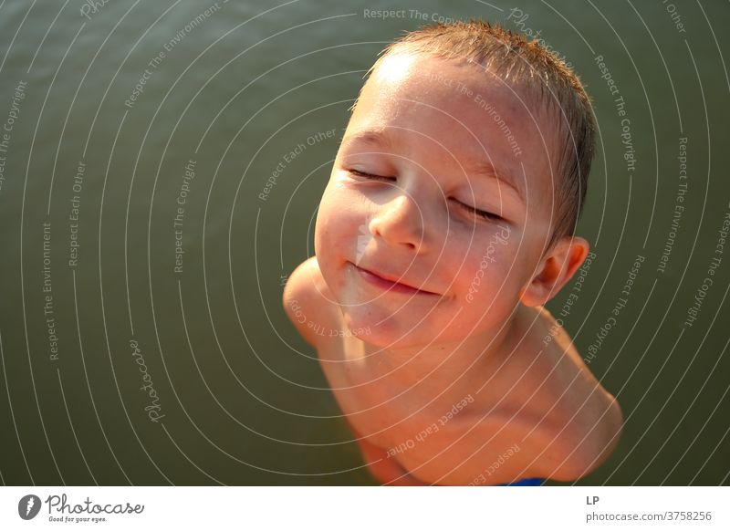 Schöner Junge, der der Sonne zugewandt ist, die Augen geschlossen geschlossene Augen Vorderansicht Oberkörper Porträt Sonnenstrahlen Kontrast Schatten Licht