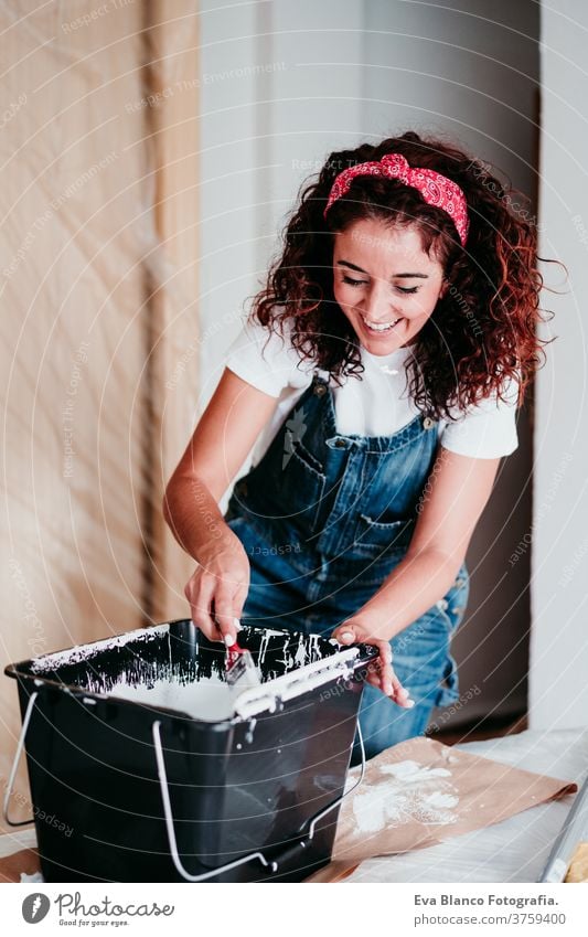 glückliche kaukasische Frau, die die Zimmerwände mit weißer Farbe streicht. Do it yourself und neues Wohnkonzept Kaukasier Malerei heimwärts Haus Bürste Glück