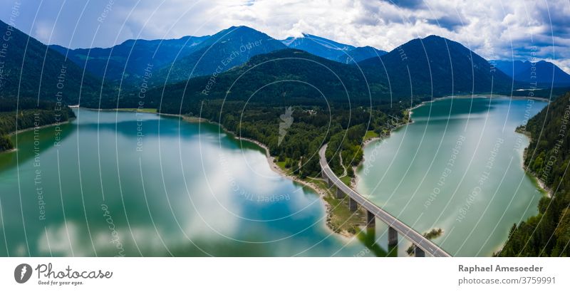 Luftpanoramaaufnahme des Sylvenstein-Staudamms an einem bewölkten Sommertag Landschaft See Isar Antenne Alpen Brücke Wasser Berge u. Gebirge Straße Bank Strand