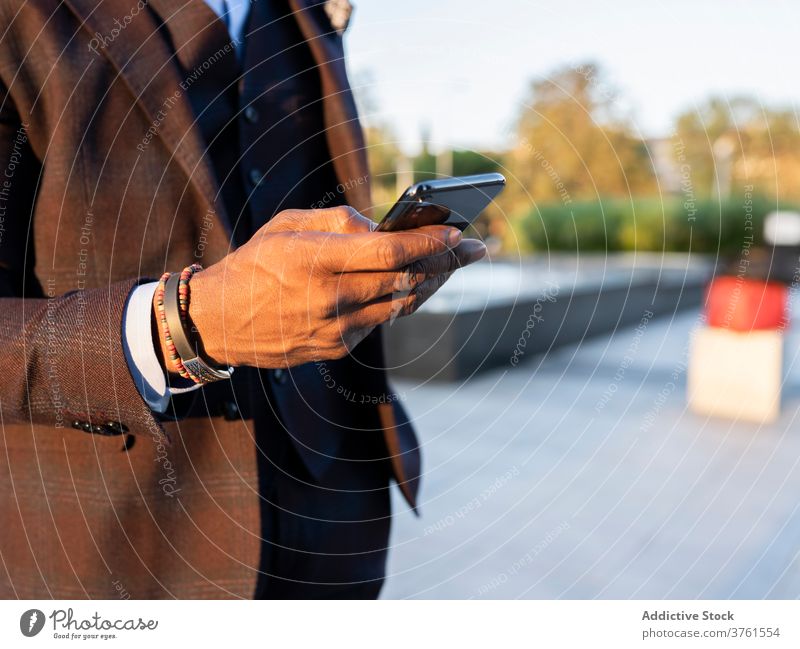 Crop männlichen Unternehmer Browsing Handy auf der Straße Geschäftsmann Anzug Großstadt Surfen Smartphone Projekt Internet Arbeit benutzend blättern ethnisch