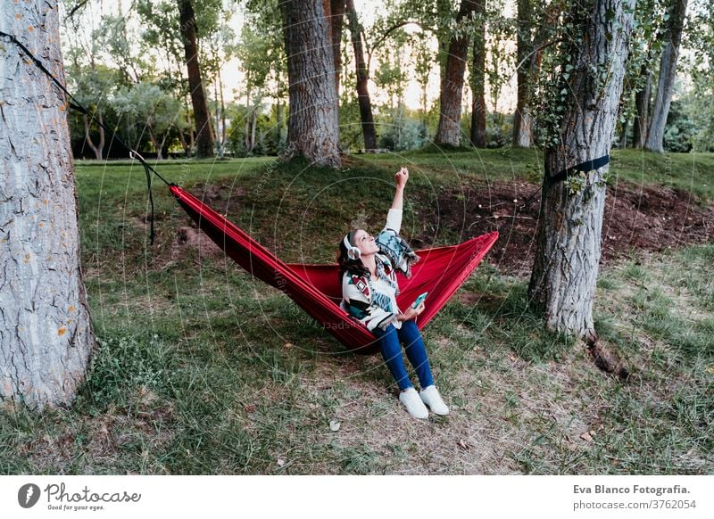 glückliche frau entspannt sich in hängematte und hört musik auf handy und headset. herbstsaison. camping konzept Headset Kopfhörer hören Musik Frau Handy