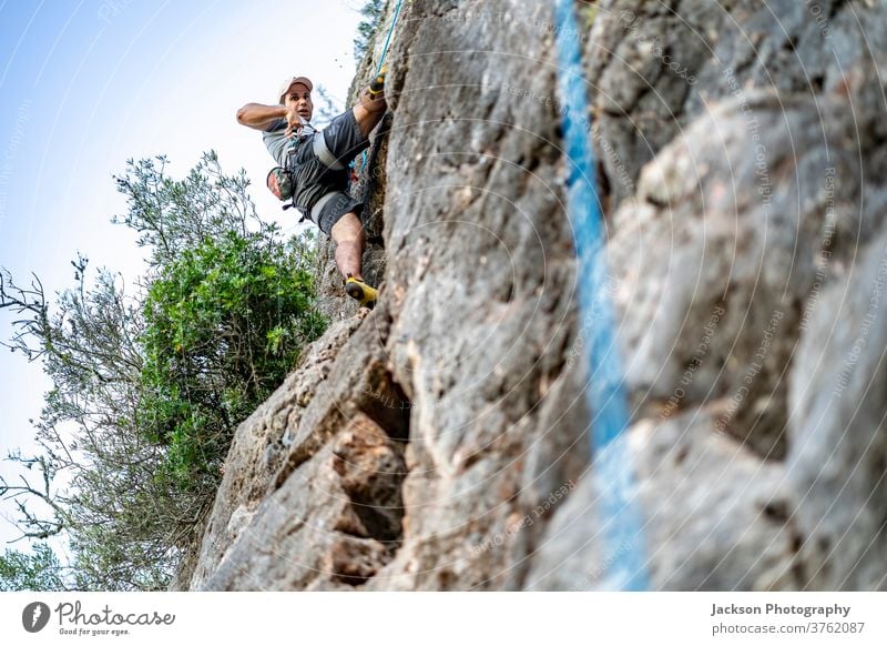 Ein Mann klettert mit einem Klettergurt auf einen Felsen Aufsteiger Klettern Portugal Abenteuer im Freien Park Natur hoch aktiv Aktivität Adrenalin Algarve Mut