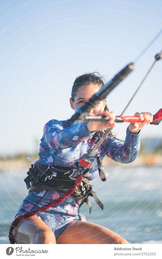 Weiblicher Kite-Surfer reitet auf dem Brett im Meer Milan Brandung Frau Mitfahrgelegenheit winken MEER platschen Sommer professionell Badeanzug passen Erholung