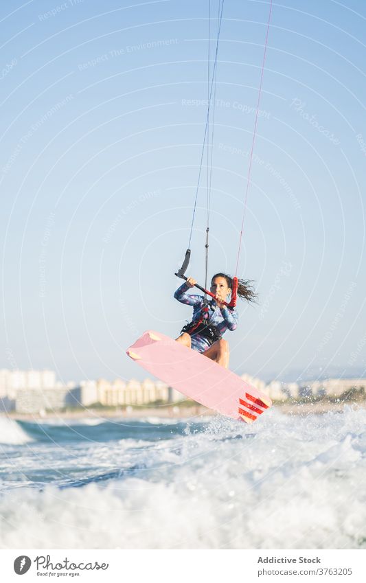 Weiblicher Kite-Surfer reitet auf dem Brett im Meer Milan Brandung Frau Mitfahrgelegenheit winken MEER platschen Sommer professionell Badeanzug passen Erholung