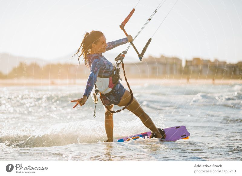 Weiblicher Kite-Surfer reitet auf dem Brett im Meer Milan Brandung Frau Mitfahrgelegenheit winken MEER platschen Sommer professionell Badeanzug passen Erholung