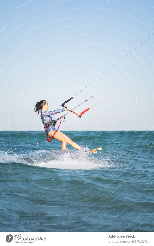 Weiblicher Kite-Surfer reitet auf dem Brett im Meer Milan Brandung Frau Mitfahrgelegenheit winken MEER platschen Sommer professionell Badeanzug passen Erholung