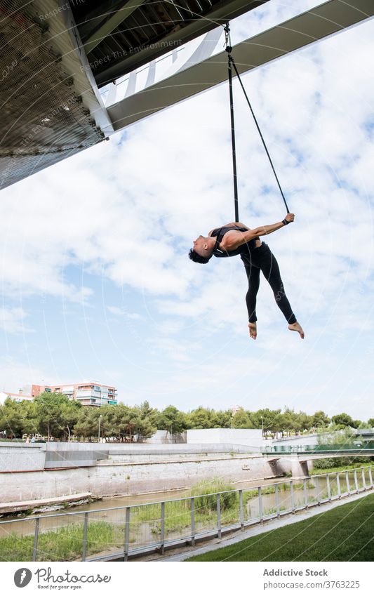 Flexibler Mann trainiert an Traggurten Antenne Gurt Turner Training gymnastisch hängen ausführen beweglich passen Park männlich Übung Energie Athlet Sport