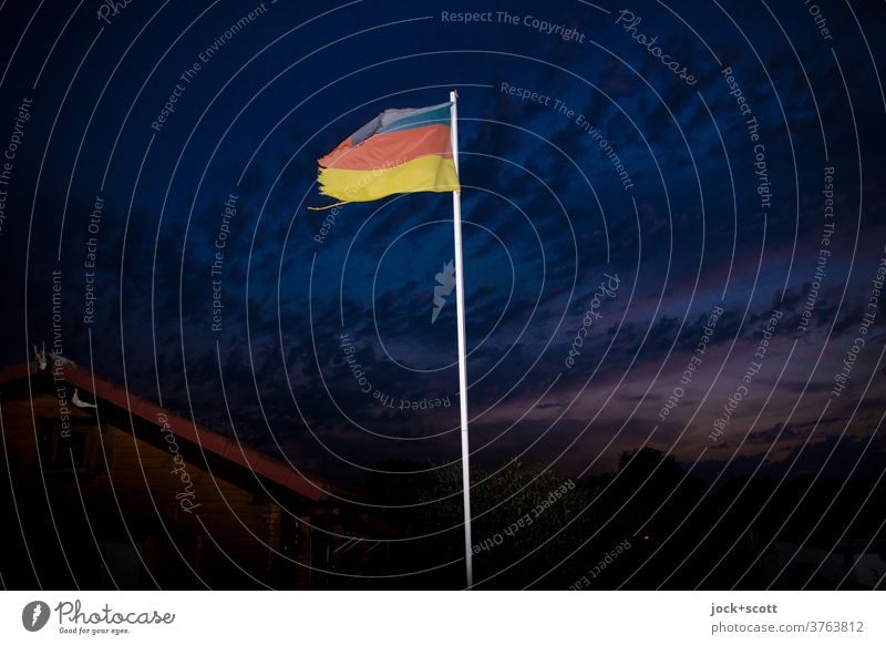 Kleingarten 2020 Urlaubsgefühl Gartenhaus Sonnenuntergang Wolken Wind Staatssymbol wehen Deutsche Flagge Fahnenmast flattern Blitzlichtaufnahme Deutschland