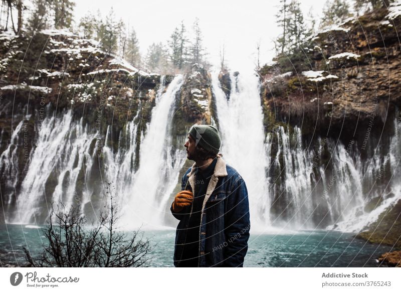 Männlicher Reisender auf Wasserfall in verschneiten bergigen Wald im Winter Tag Mann Schnee fließen Natur Person Landschaft Pool männlich kalt strömen malerisch