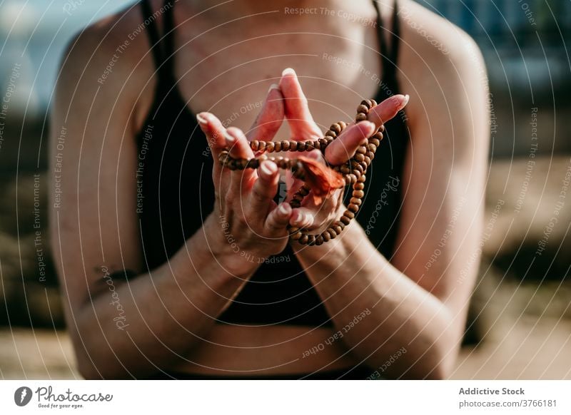 Anonyme Frau mit Rosenkranz macht Yoga am Strand Wulst Asana üben Gebet Pose Windstille beweglich felsig Ufer Gesundheit ruhig schlank Gelassenheit Zen