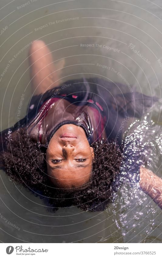 Hübsche junge schwarze Frau mit Blick in die Kamera ins Wasser Afro-Look Porträt Mobile Urlaub Sommer schauende Kamera Strand reisen Menschen Model MEER schön