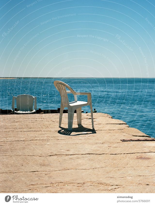 Sonnenplatz Meerblick Stuhl Plastikstuhl Horizont Pause ausblick Mittagssonne Wolkenloser Himmel blau