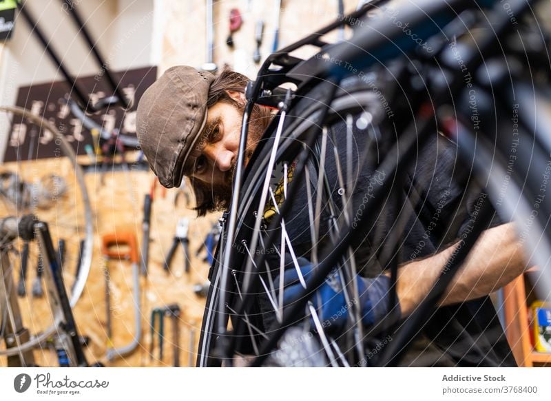 Reparateur repariert Fahrradrad in der Werkstatt Reparatur Mann Mechaniker Rad Speiche fixieren Flugzeugwartung Beruf Dienst männlich Vollbart reif