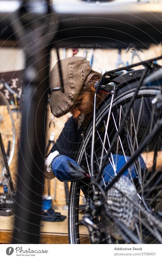 Reparateur repariert Fahrradrad in der Werkstatt Reparatur Mann Mechaniker Rad Speiche fixieren Flugzeugwartung Beruf Dienst männlich Vollbart reif