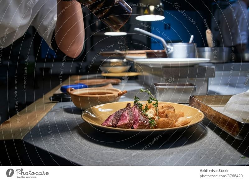 Appetitliches Stück Rindfleisch auf einem Teller in der Küche Scheibe Restaurant Speise Gewürz Koch hinzufügen bestäuben Fleisch Küchenchef Lebensmittel