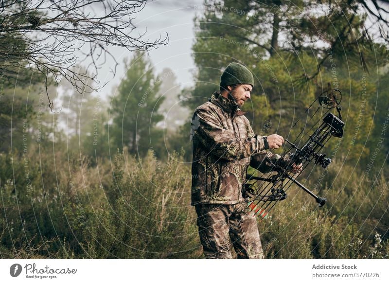 Mann mit Bogen im Wald bei der Jagd Jäger Schleife jagen Tarnung Gerät ausrichten Verbindung Wälder männlich Bogensport modern Pfeil Fähigkeit Zeitgenosse