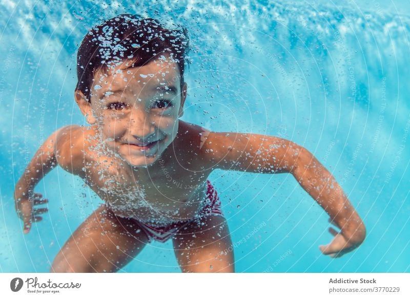 Fröhlicher Junge im Schwimmbad schwimmen Pool Kind Sinkflug spielerisch Freude Kindheit Urlaub Sommer Spaß haben Wasser Erholung aqua heiter Badeanzug