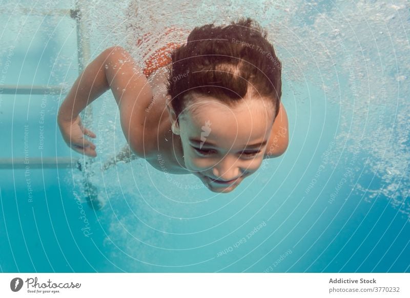 Fröhlicher Junge im Schwimmbad schwimmen Pool Kind Sinkflug spielerisch Freude Kindheit Urlaub Sommer Spaß haben Wasser Erholung aqua heiter Badeanzug