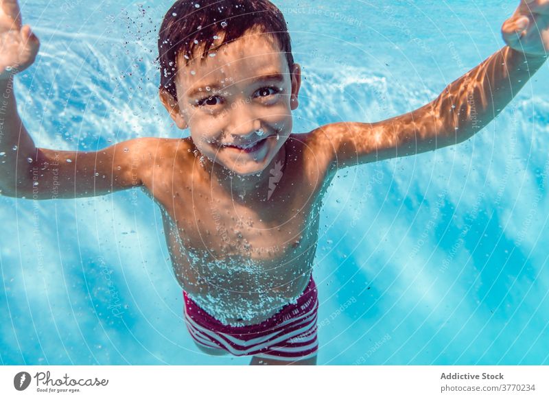 Fröhlicher Junge im Schwimmbad schwimmen Pool Kind Sinkflug spielerisch Freude Kindheit Urlaub Sommer Spaß haben Wasser Erholung aqua heiter Badeanzug