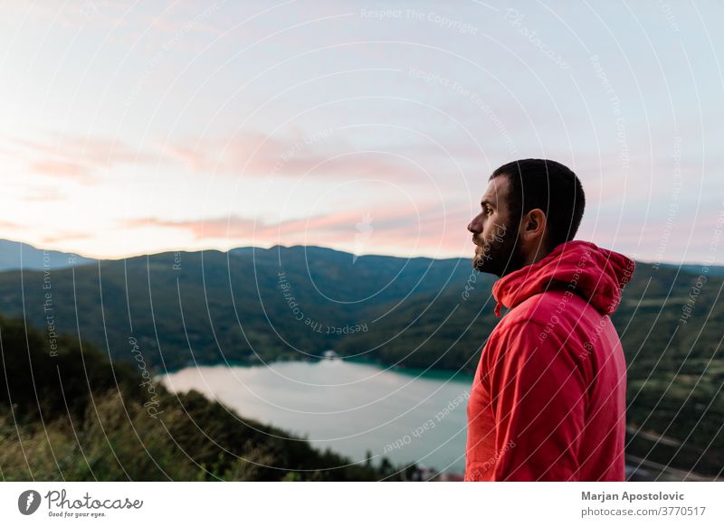 Junger Mann genießt den Blick auf den See bei Sonnenuntergang Abenteuer abenteuerlustig allein lässig Kontemplation Morgendämmerung Ausflugsziel Abenddämmerung