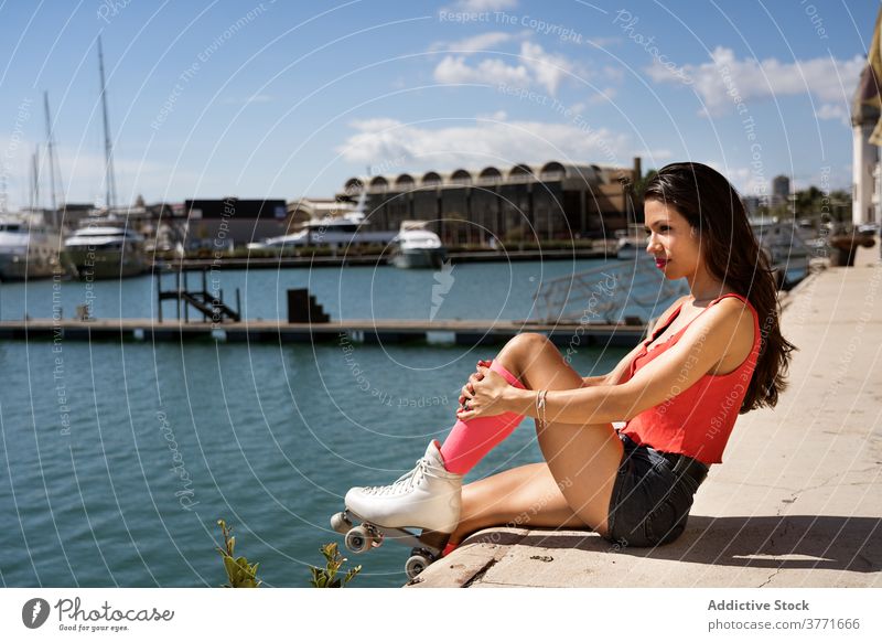 Schlanke Frau in Rollschuhen auf der Seebrücke Rolle Schlittschuh retro Sitzen Großstadt aktiv schlank Pier hölzern Sommer Hobby passen Sport Stil modern Stadt