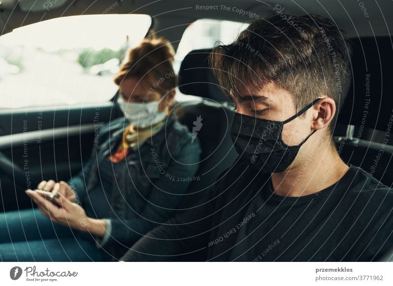 Mann und Frau sitzen in einem Auto und benutzen Smartphones und tragen die Gesichtsmasken, um eine Virusinfektion zu vermeiden Kaukasier covid-19 Lifestyle