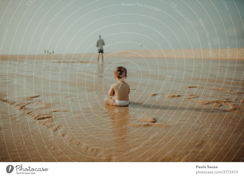 Rückansicht eines am Strand spielenden Kindes Kleinkind Kindheit Badeurlaub Sand Sandstrand Küste Natur Spielen Farbfoto Sommerurlaub Erholung Außenaufnahme