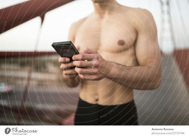 Training der Läufer ohne Hemd auf der roten Brücke und Blick auf die Telefonstatistik laufen Mann stark passen Fitness Steg Fußweg Männer männlich