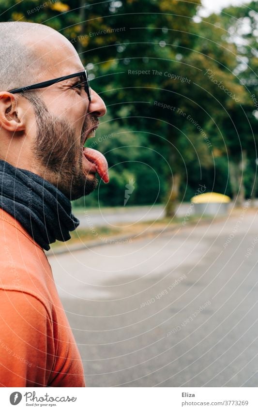 Ein Mann streckt angewidert die Zunge heraus. Ekel Zunge rausstrecken bäh Profil nicht mögen igitt bizarr Grimasse Unwille trotz Glatze Brille