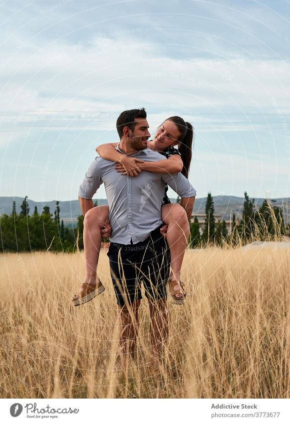 Glückliches Paar kuscheln im Feld im Sommer Huckepack Mitfahrgelegenheit Liebe Angebot Partnerschaft Wiese Wochenende Landschaft getrocknet Natur heiter Lächeln